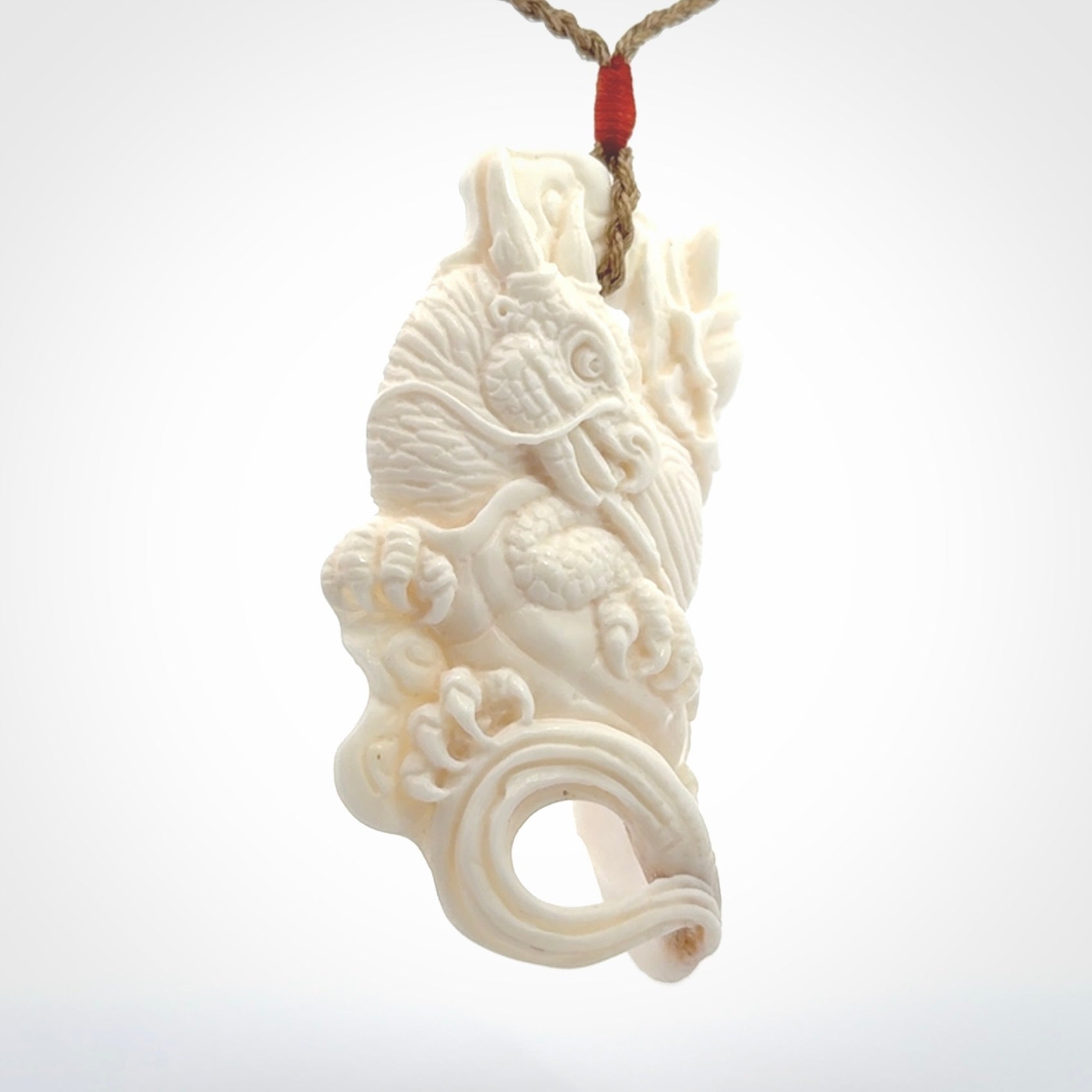 This is a hand carved bone baby dragon pendant. It is made from bone and has an adjustable tan coloured cord. This is a large sized necklace and is a very unique, one only, pendant that is a piece for art lovers.