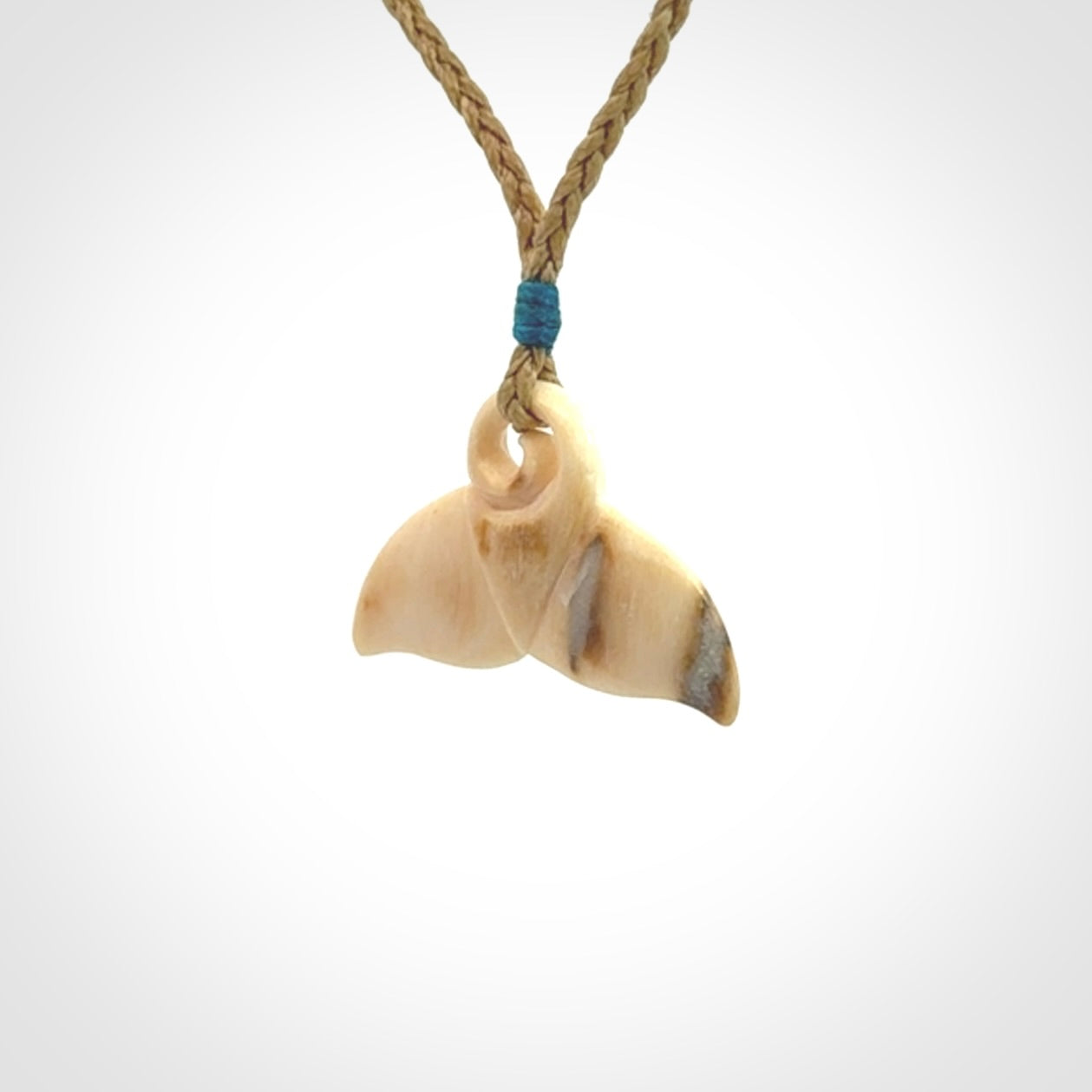 This photo shows a small whaletail pendant that we have carved from a light honey coloured piece of Woolly Mammoth tusk. It is suspended on a tan cord that is length adjustable.