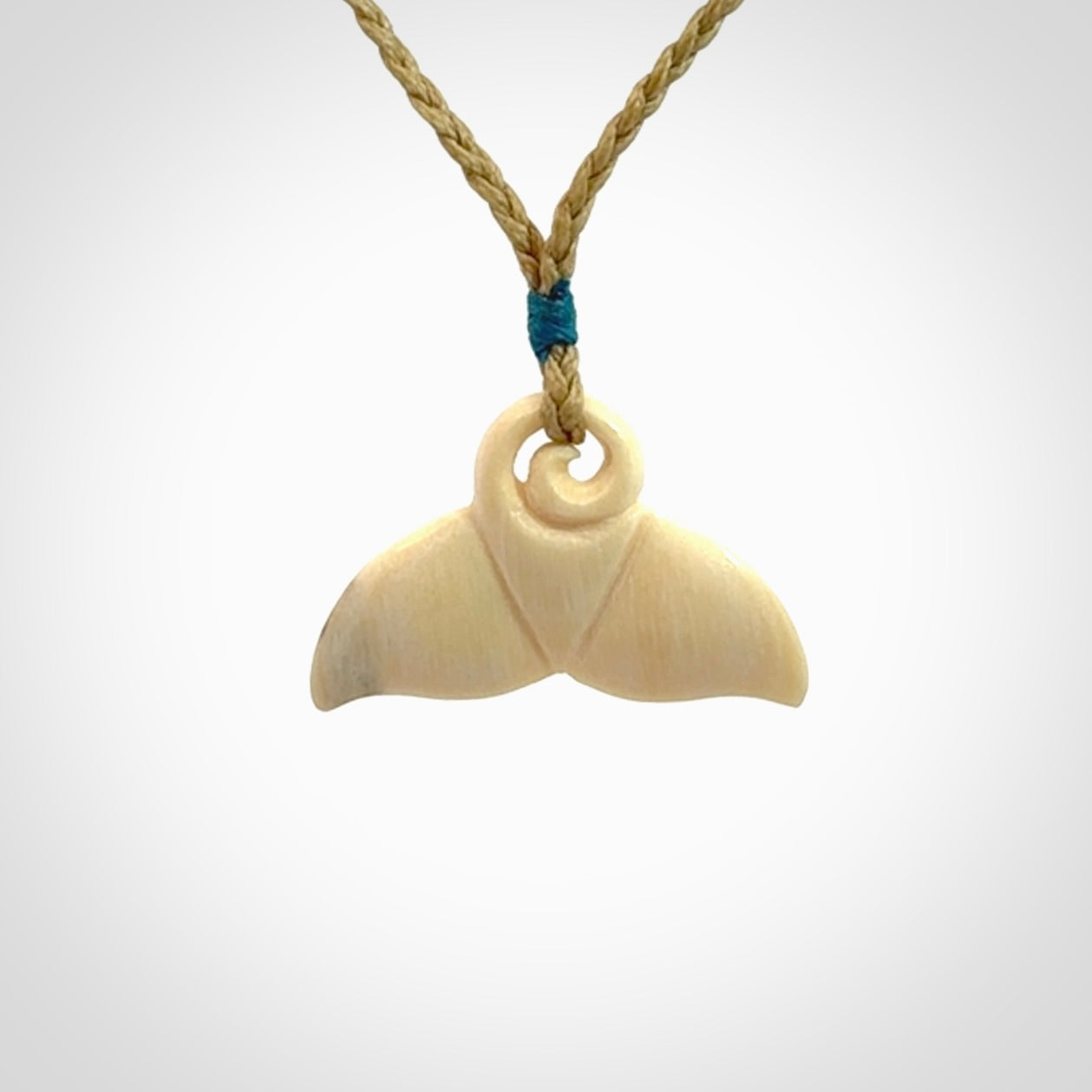 This photo shows a small whaletail pendant that we have carved from a light honey coloured piece of Woolly Mammoth tusk. It is suspended on a tan cord that is length adjustable.