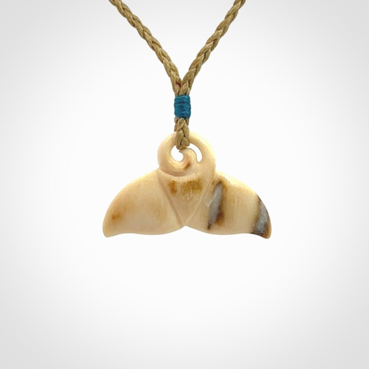 This photo shows a small whaletail pendant that we have carved from a light honey coloured piece of Woolly Mammoth tusk. It is suspended on a tan cord that is length adjustable.