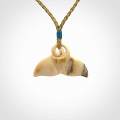 This photo shows a small whaletail pendant that we have carved from a light honey coloured piece of Woolly Mammoth tusk. It is suspended on a tan cord that is length adjustable.