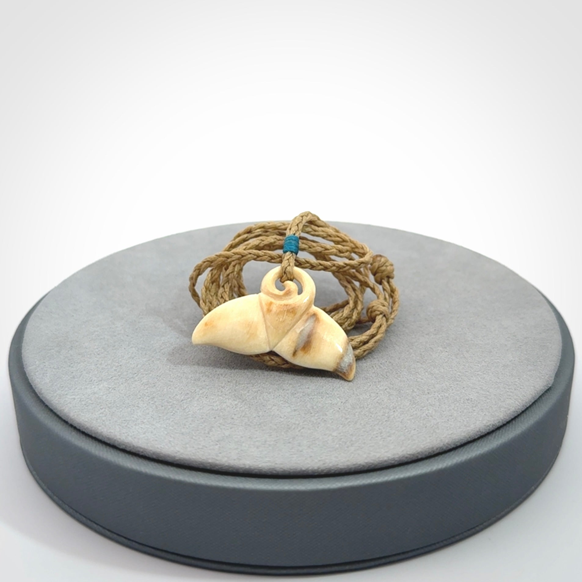 This photo shows a small whaletail pendant that we have carved from a light honey coloured piece of Woolly Mammoth tusk. It is suspended on a tan cord that is length adjustable.