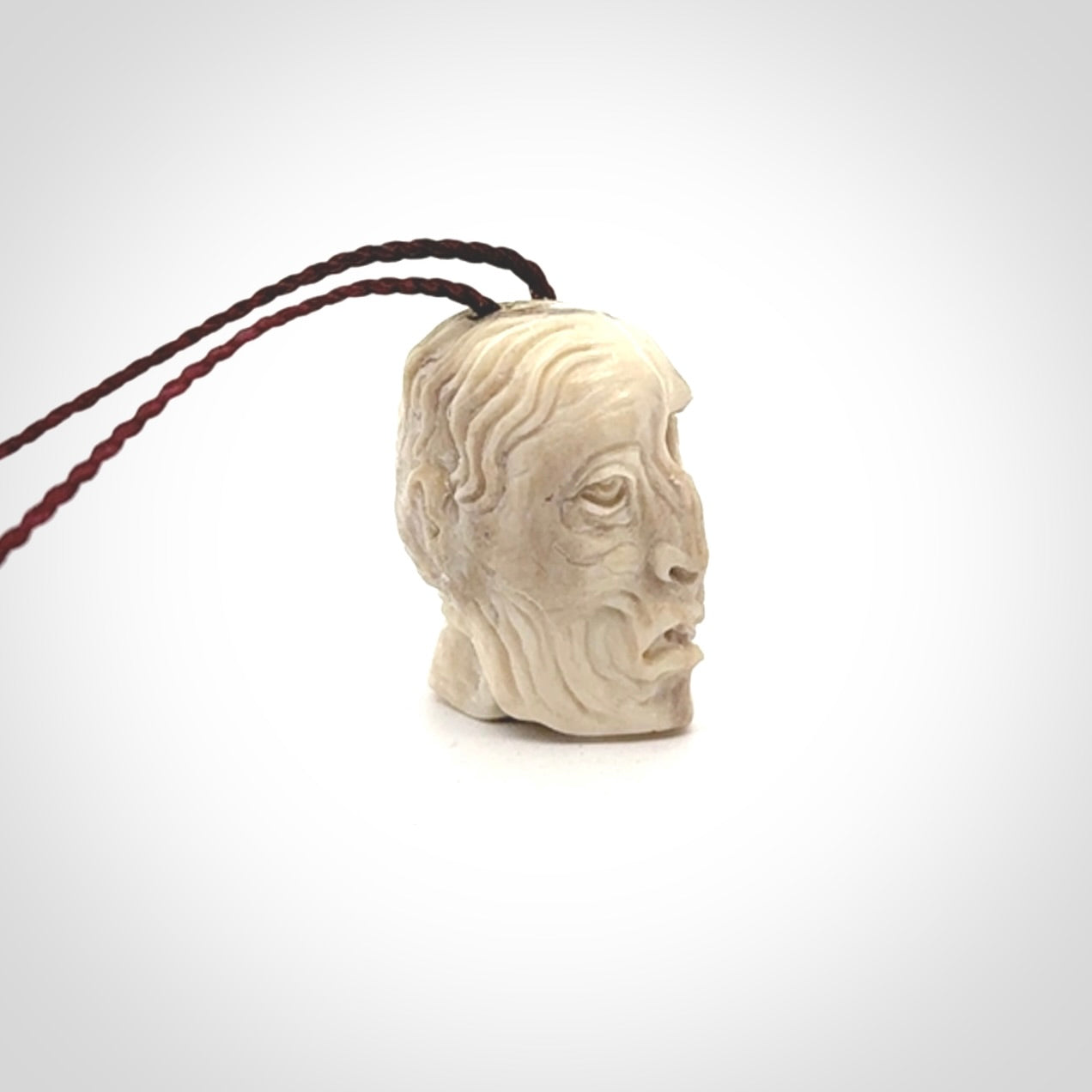 This photo shows a mummy skull pendant hand carved in deer antler. It is provided with a plaited cord necklace which is length adjustable.