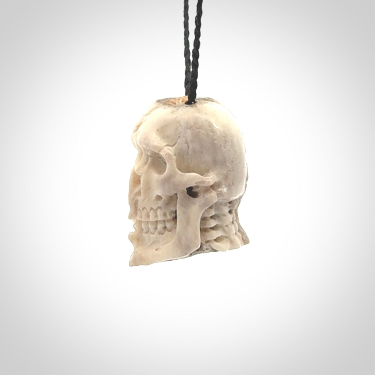 This photo shows a mummy skull pendant hand carved in deer antler. It is provided with a plaited cord necklace which is length adjustable.