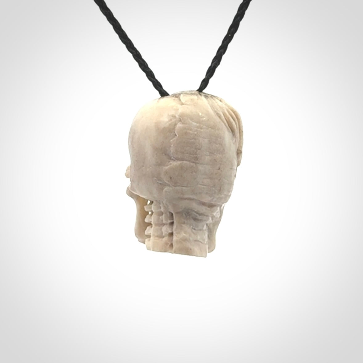 This photo shows a mummy skull pendant hand carved in deer antler. It is provided with a plaited cord necklace which is length adjustable.