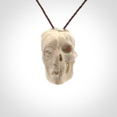 This photo shows a mummy skull pendant hand carved in deer antler. It is provided with a plaited cord necklace which is length adjustable.