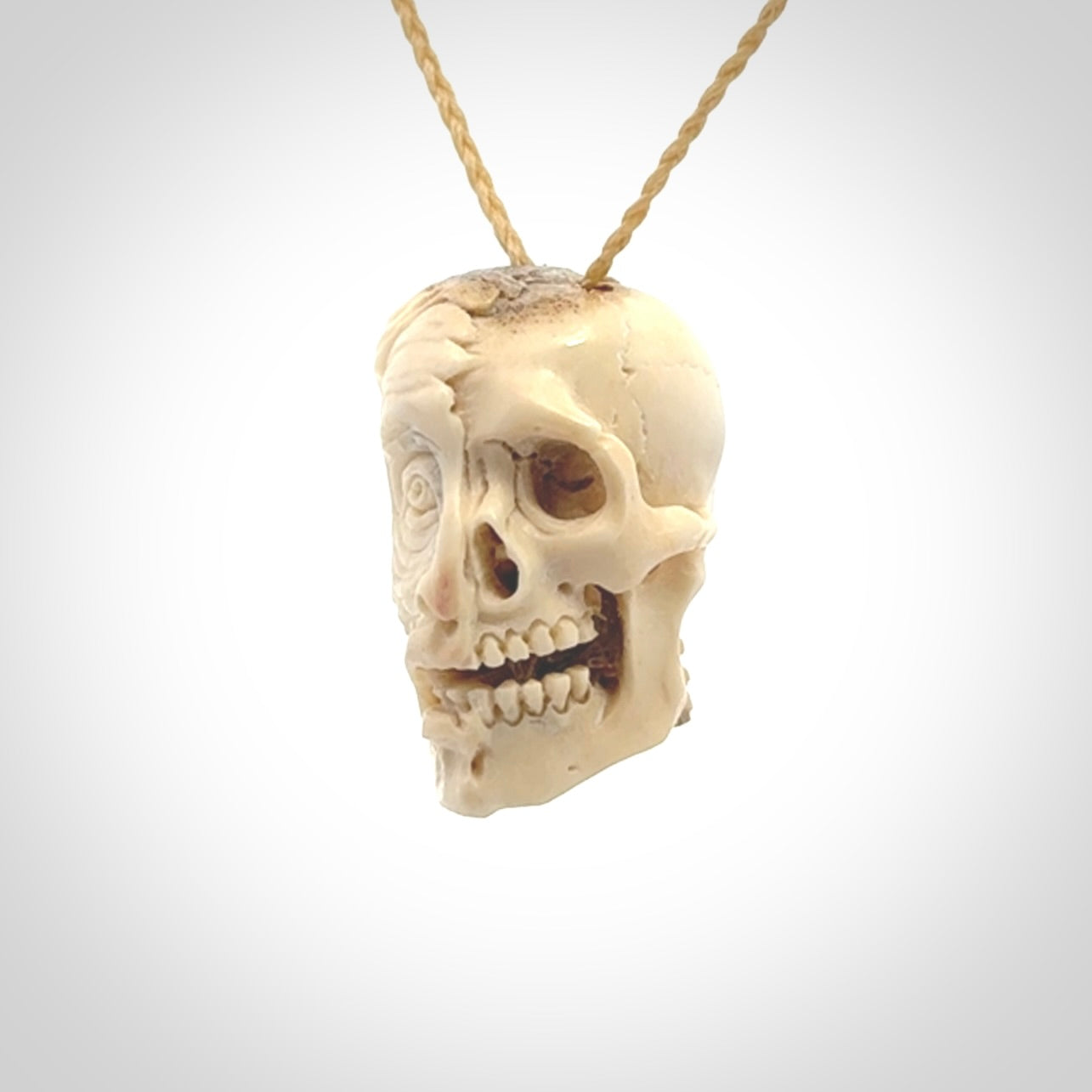 This photo shows a mummy skull pendant hand carved in deer antler. It is provided with a plaited cord necklace which is length adjustable.