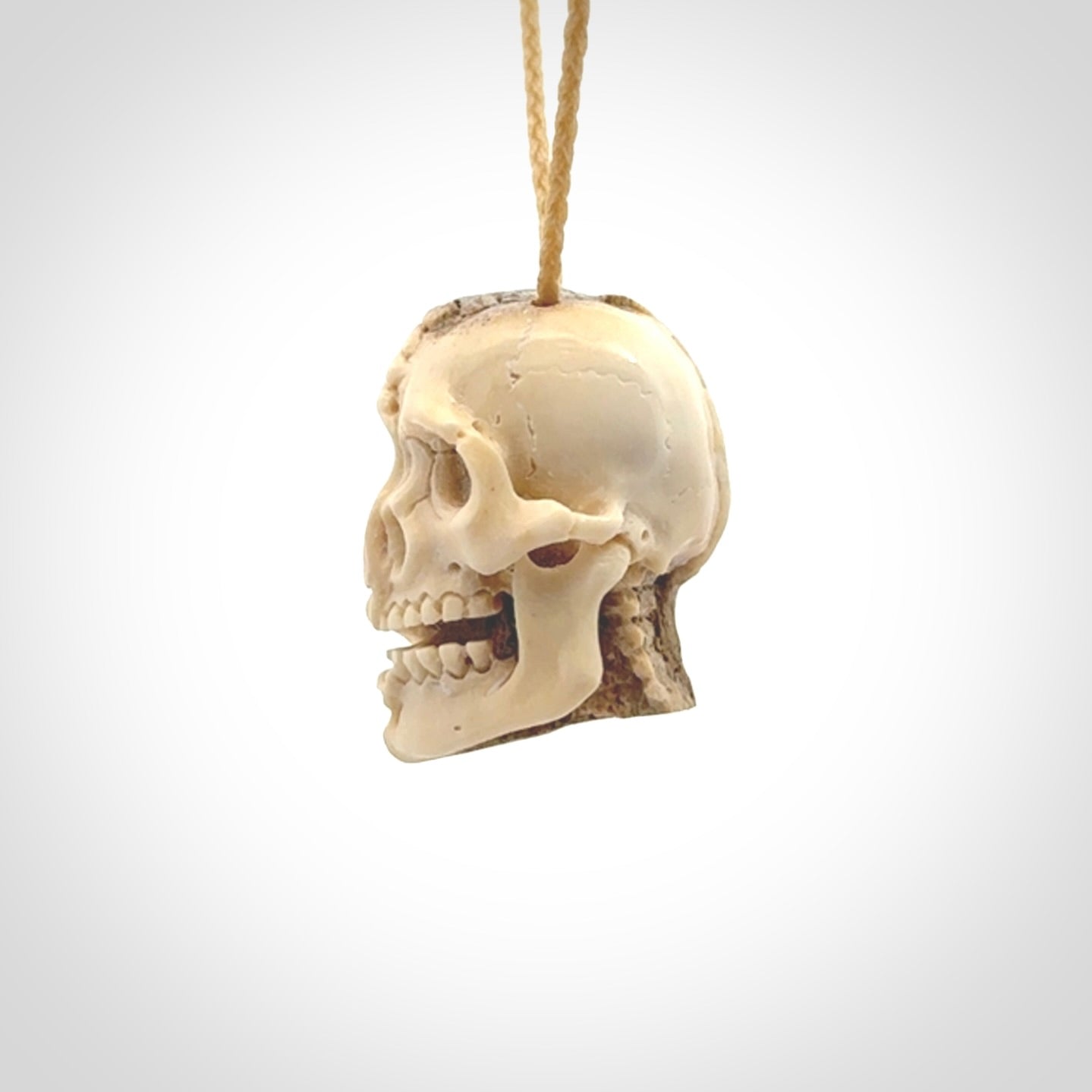 This photo shows a mummy skull pendant hand carved in deer antler. It is provided with a plaited cord necklace which is length adjustable.