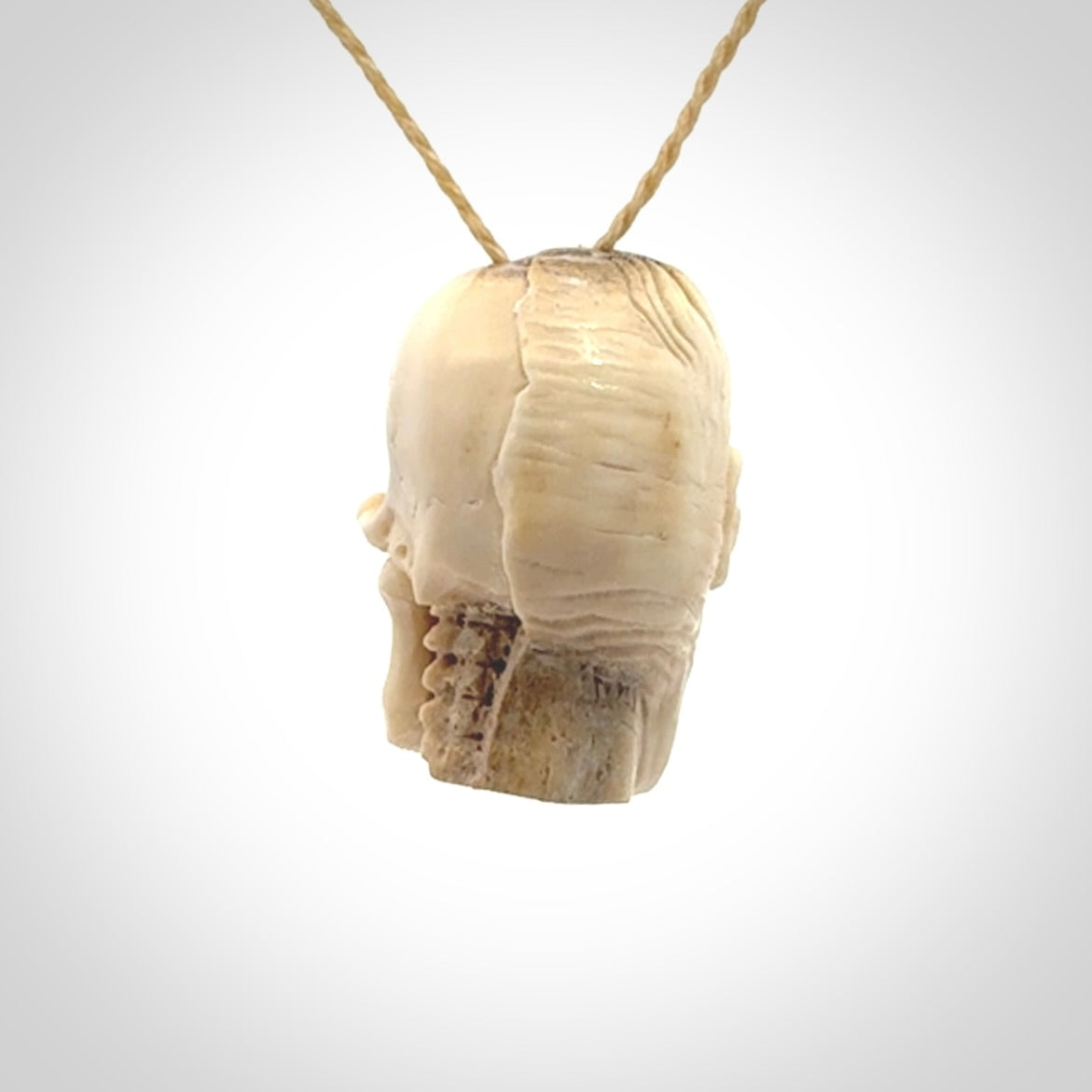 This photo shows a mummy skull pendant hand carved in deer antler. It is provided with a plaited cord necklace which is length adjustable.