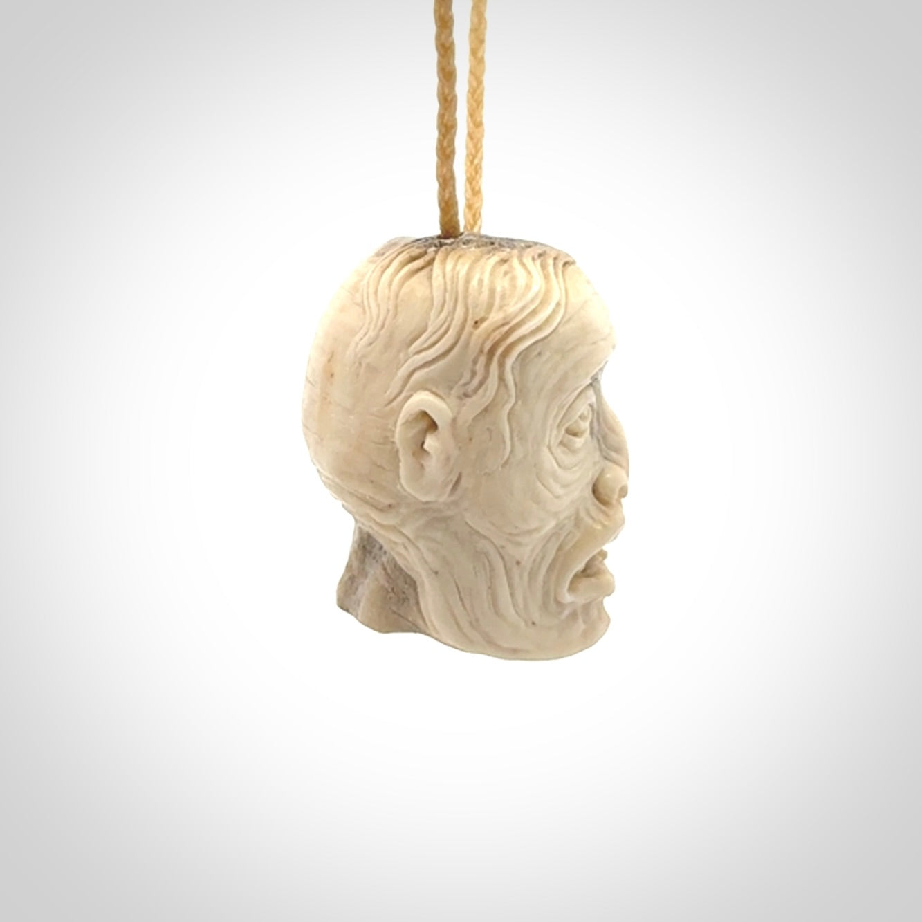 This photo shows a mummy skull pendant hand carved in deer antler. It is provided with a plaited cord necklace which is length adjustable.