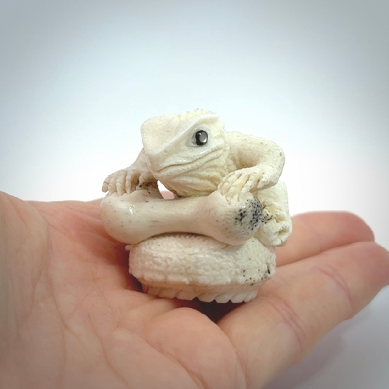 Hand carved incredible tuatara with dinosaur bone carving. A stunning work of art, beautifully replicating a tuatara holding a dinosaur bone. A one off collectors item that has been hand crafted to be worn or displayed.