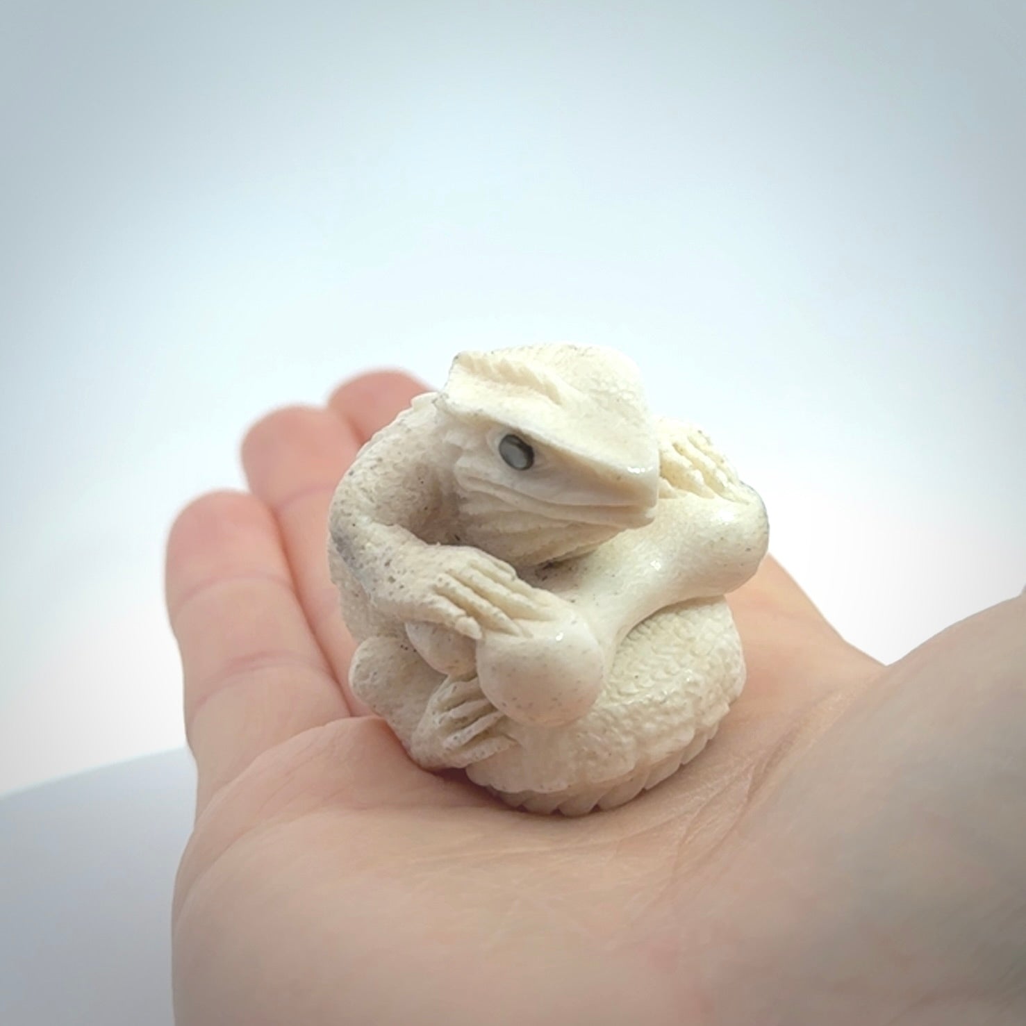 Hand carved incredible tuatara with dinosaur bone carving. A stunning work of art, beautifully replicating a tuatara holding a dinosaur bone. A one off collectors item that has been hand crafted to be worn or displayed.