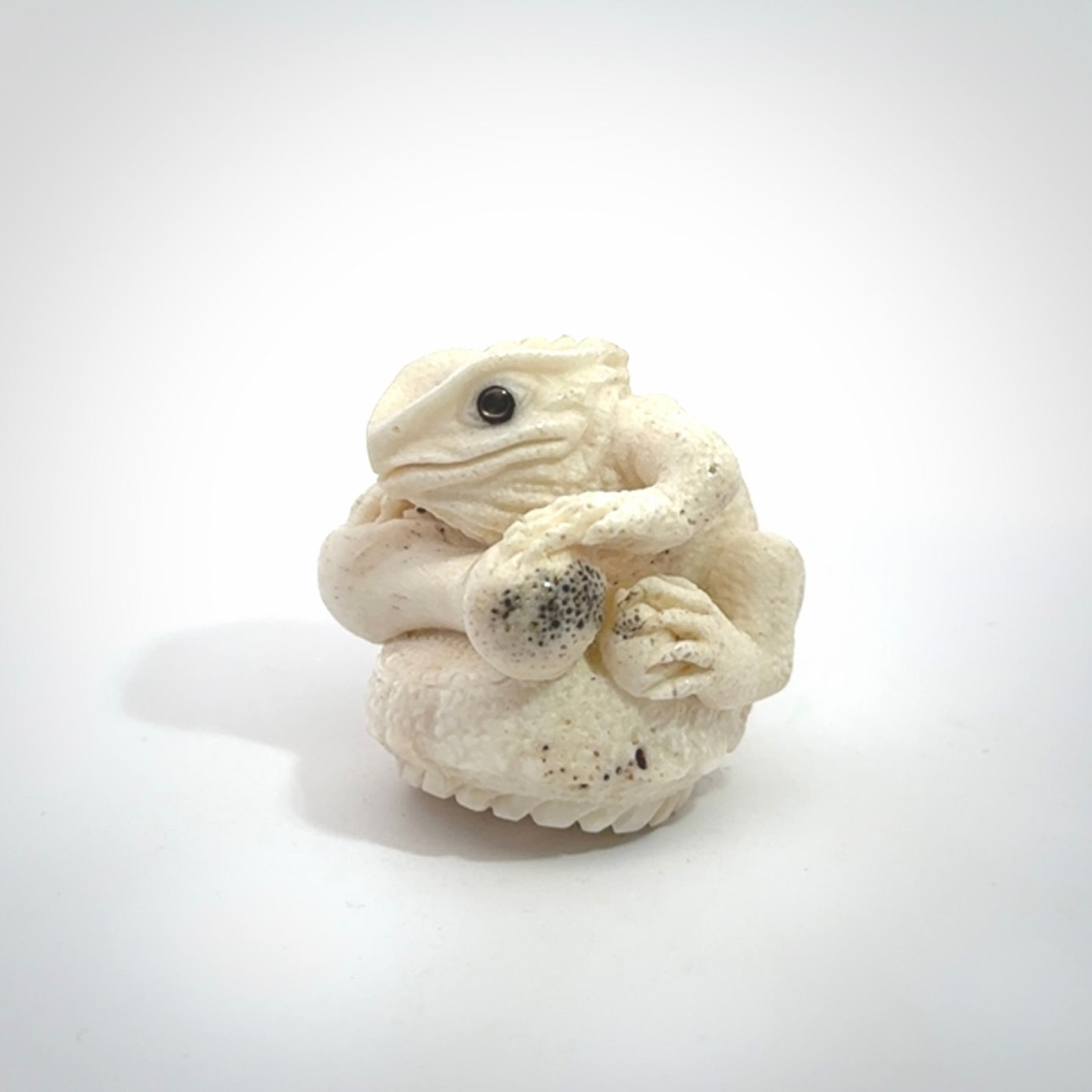Hand carved incredible tuatara with dinosaur bone carving. A stunning work of art, beautifully replicating a tuatara holding a dinosaur bone. A one off collectors item that has been hand crafted to be worn or displayed.
