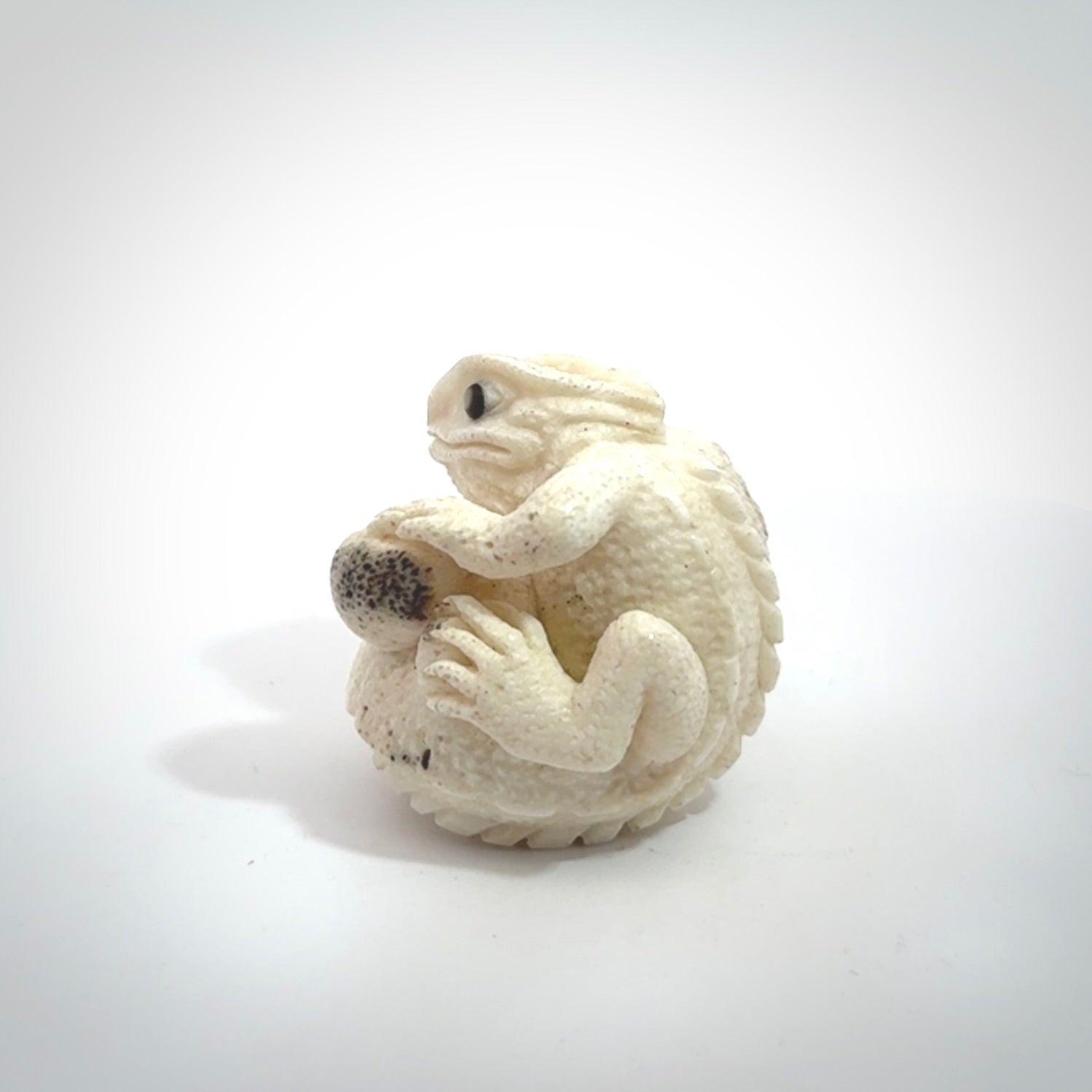 Hand carved incredible tuatara with dinosaur bone carving. A stunning work of art, beautifully replicating a tuatara holding a dinosaur bone. A one off collectors item that has been hand crafted to be worn or displayed.