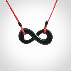 This piece is a fine, delicate eternity shaped pendant. It was carved from a lovely dark piece of black jade. It is suspended on an red plaited cord that is length adjustable.
