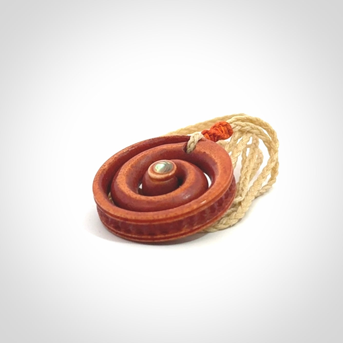 A hand carved and intricate koru pendant made for us by Yuri Terenyi. It is suspended from a oat cord with a orange floret and the necklace is adjustable.