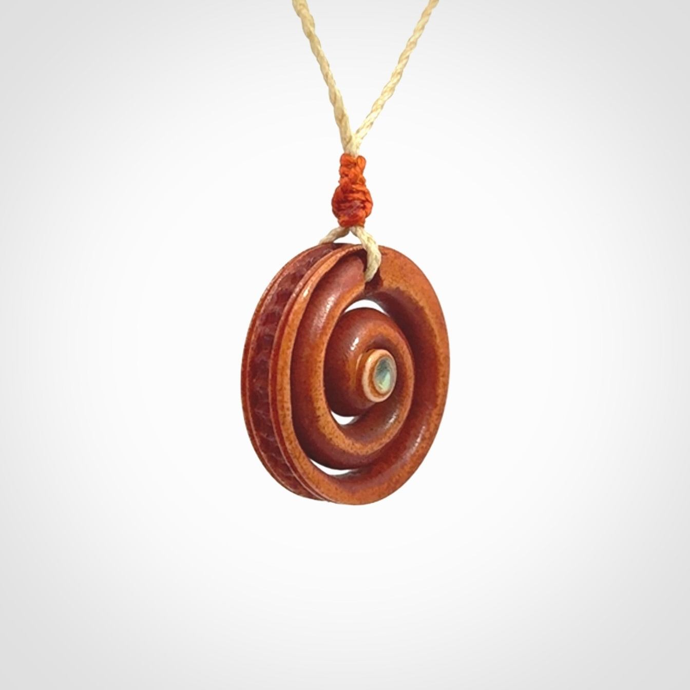 A hand carved and intricate koru pendant made for us by Yuri Terenyi. It is suspended from a oat cord with a orange floret and the necklace is adjustable.