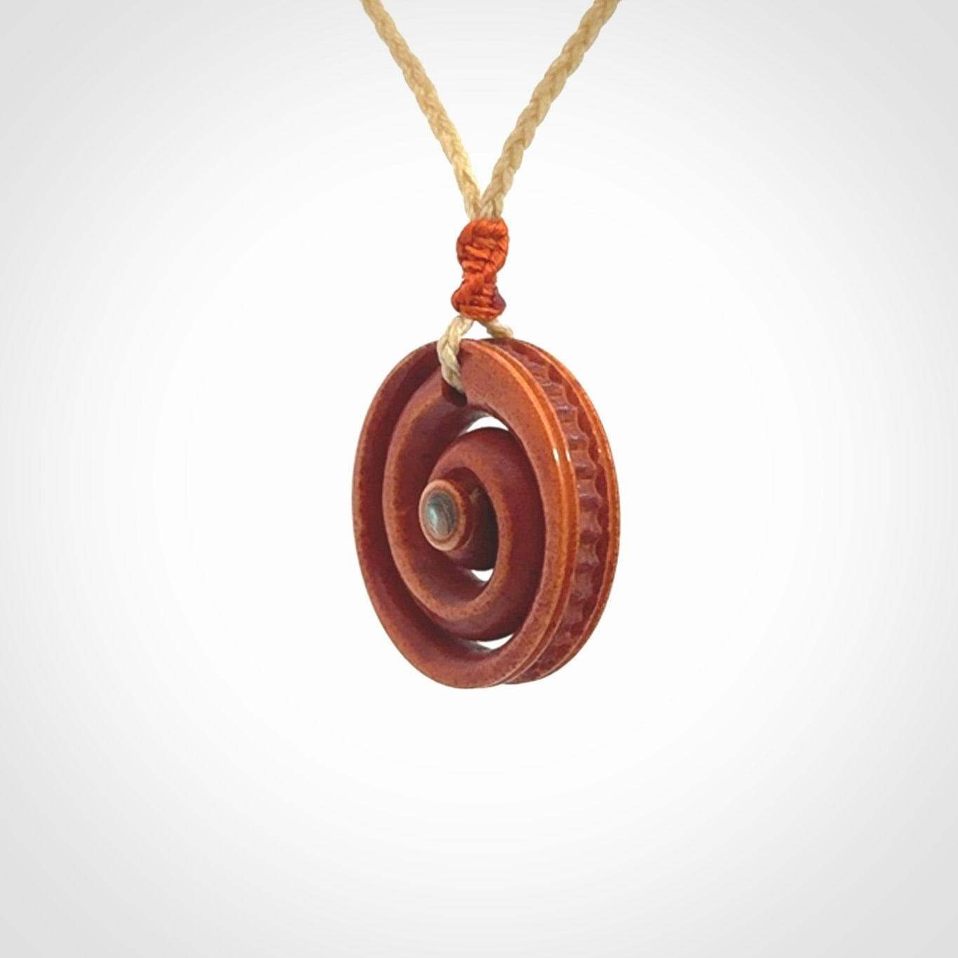A hand carved and intricate koru pendant made for us by Yuri Terenyi. It is suspended from a oat cord with a orange floret and the necklace is adjustable.