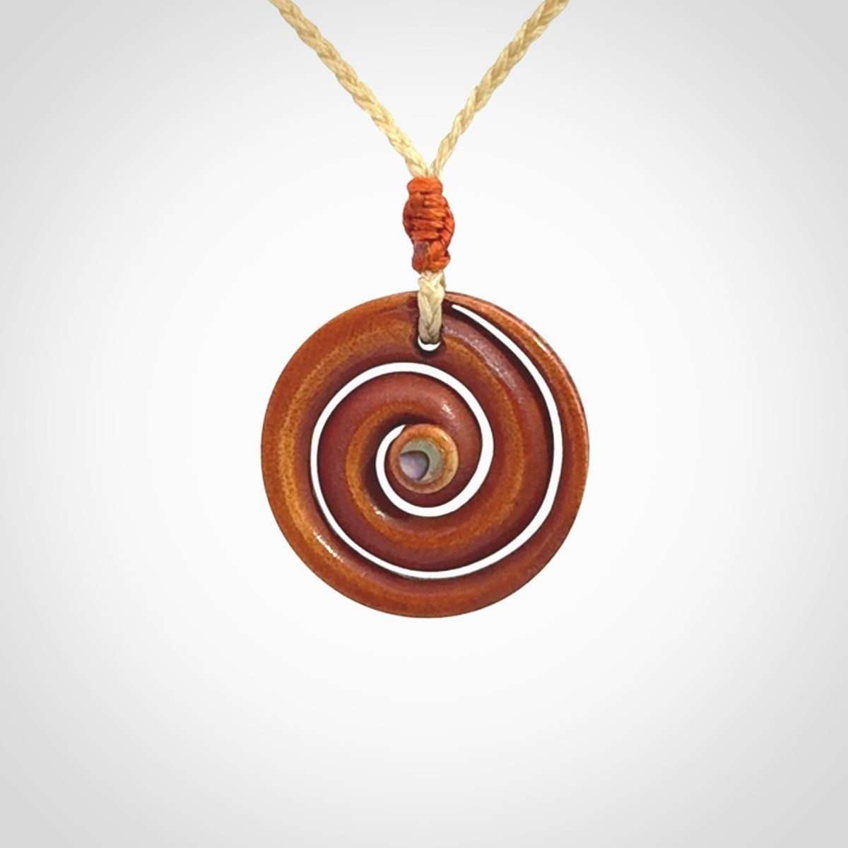 A hand carved and intricate koru pendant made for us by Yuri Terenyi. It is suspended from a oat cord with a orange floret and the necklace is adjustable.