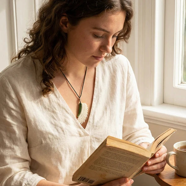Woman reading a book wearing a bone and jade wing pendant