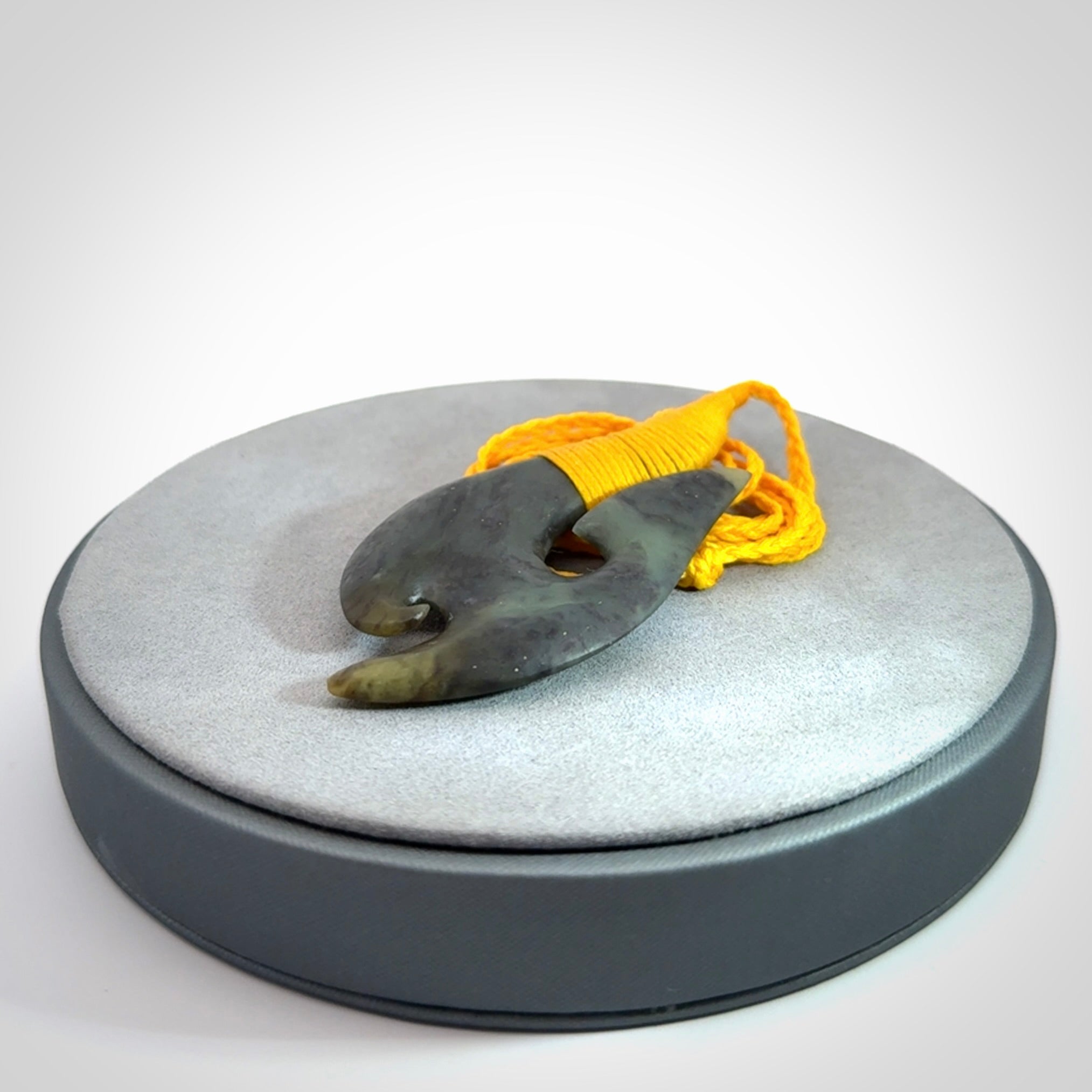 This is a beautiful jade hook with a little decorative koru carved into the bottom. It is a chunky piece but beautifully balanced so doesn't look heavy. The cord and the binding on the top is a yellow colour.