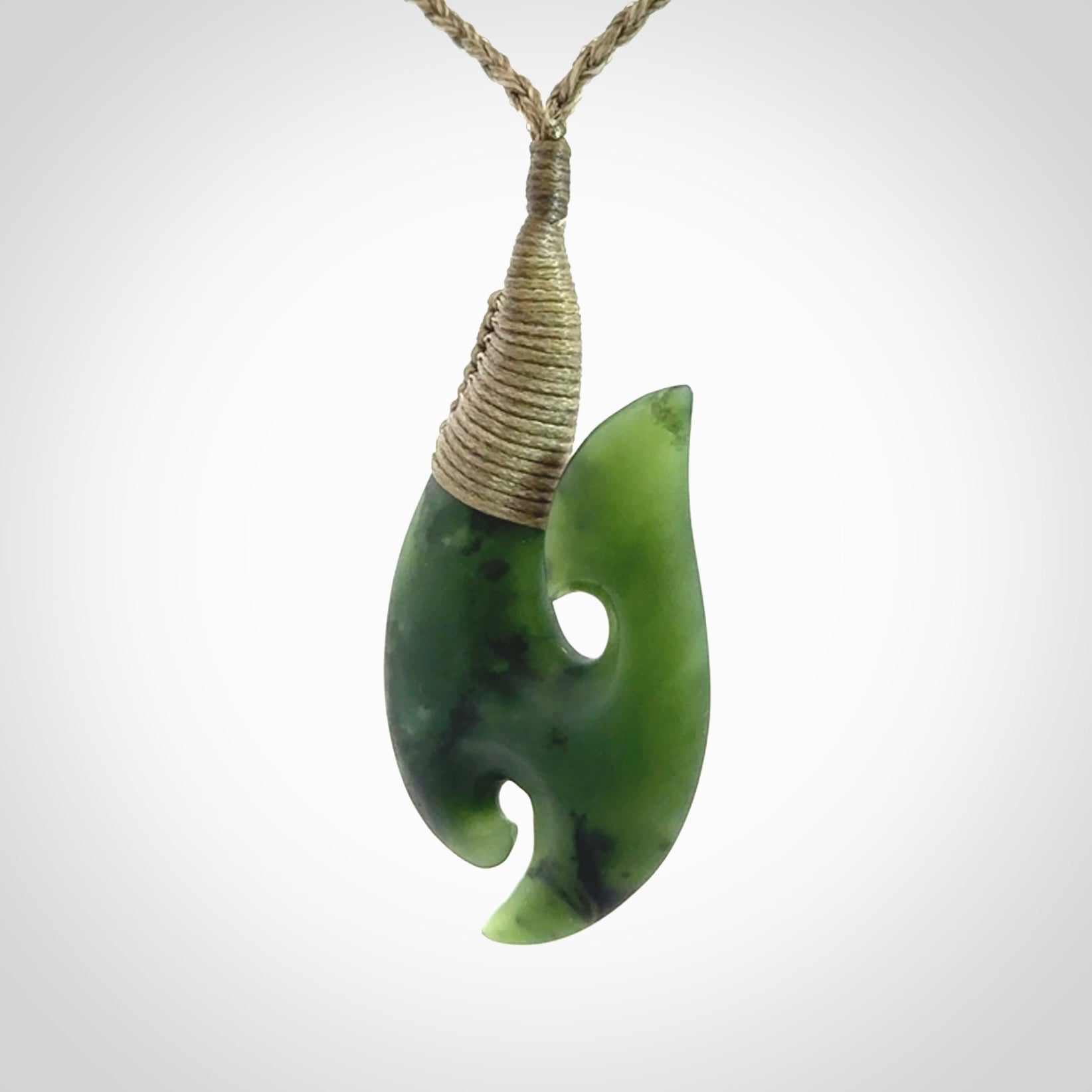 This is a beautiful jade hook with a little decorative koru carved into the bottom. It is a chunky piece but beautifully balanced so doesn't look heavy. The cord and the binding on the top is a khaki colour.
