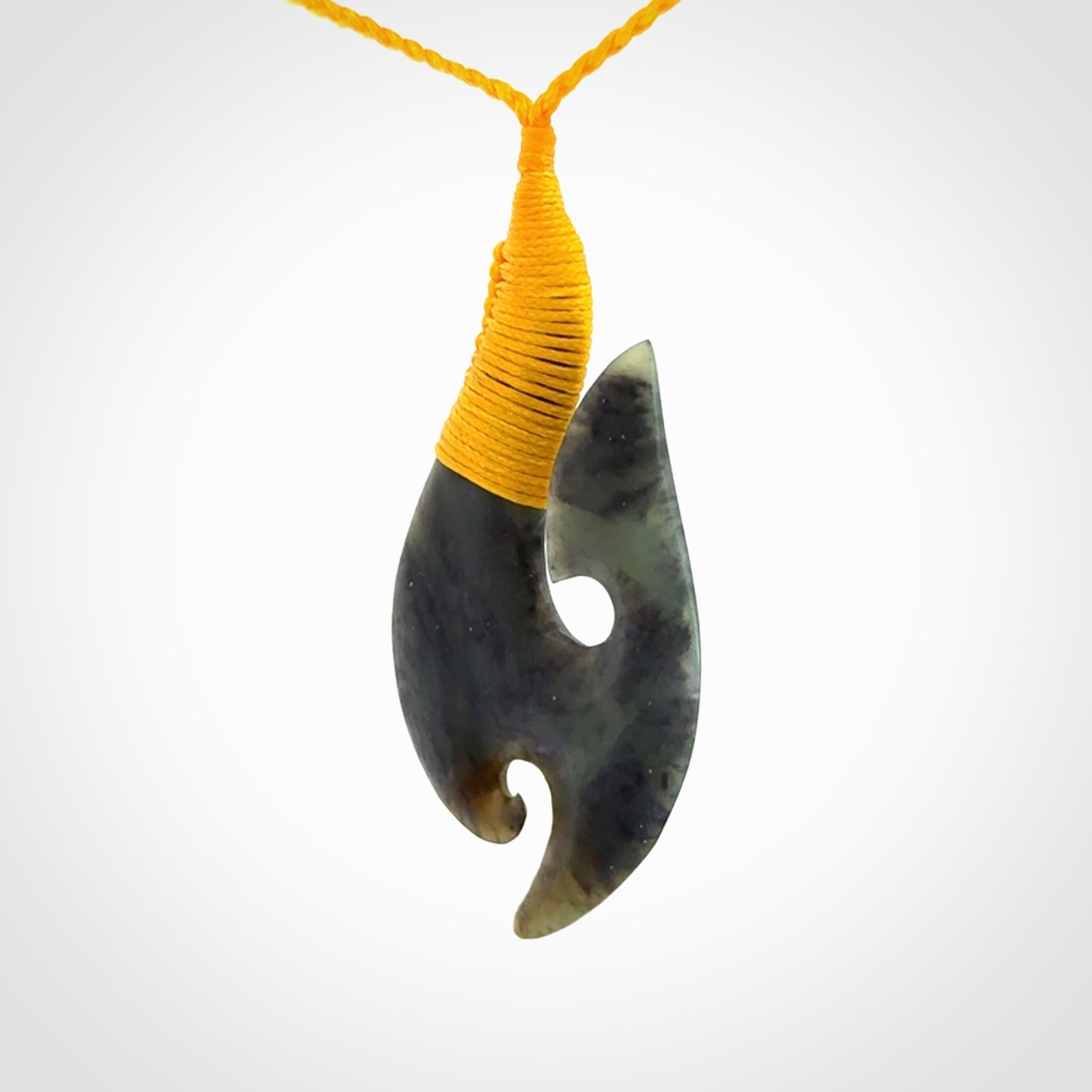 This is a beautiful jade hook with a little decorative koru carved into the bottom. It is a chunky piece but beautifully balanced so doesn't look heavy. The cord and the binding on the top is a yellow colour.
