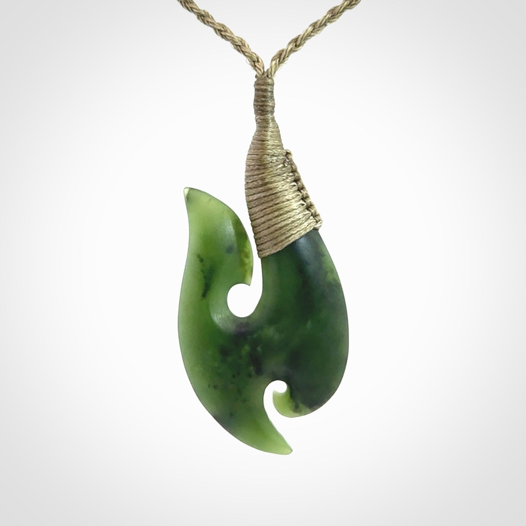 This is a beautiful jade hook with a little decorative koru carved into the bottom. It is a chunky piece but beautifully balanced so doesn't look heavy. The cord and the binding on the top is a khaki colour.