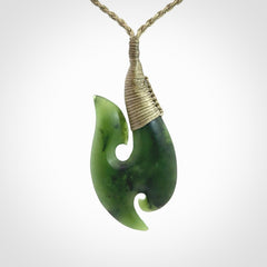 This is a beautiful jade hook with a little decorative koru carved into the bottom. It is a chunky piece but beautifully balanced so doesn't look heavy. The cord and the binding on the top is a khaki colour.