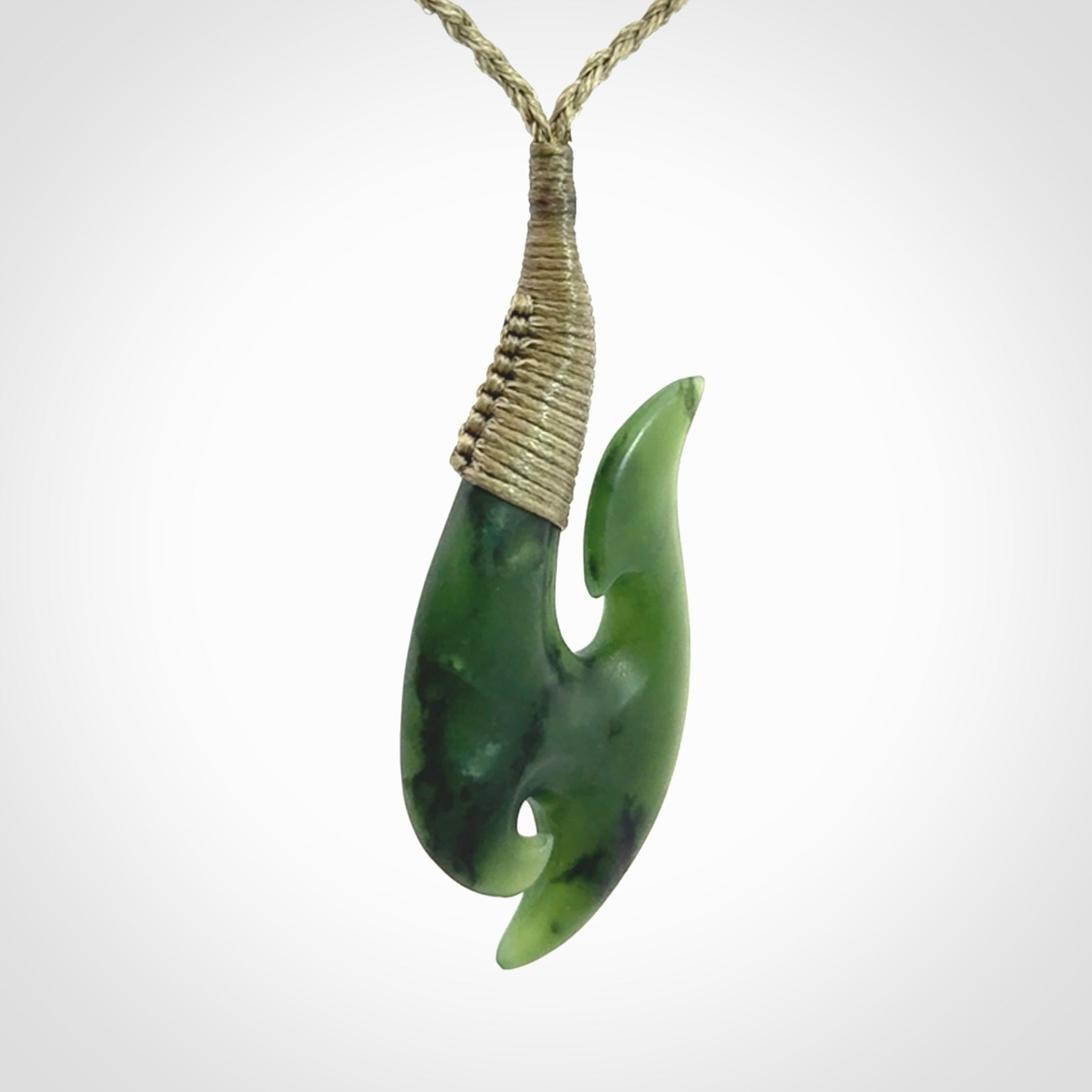 This is a beautiful jade hook with a little decorative koru carved into the bottom. It is a chunky piece but beautifully balanced so doesn't look heavy. The cord and the binding on the top is a khaki colour.