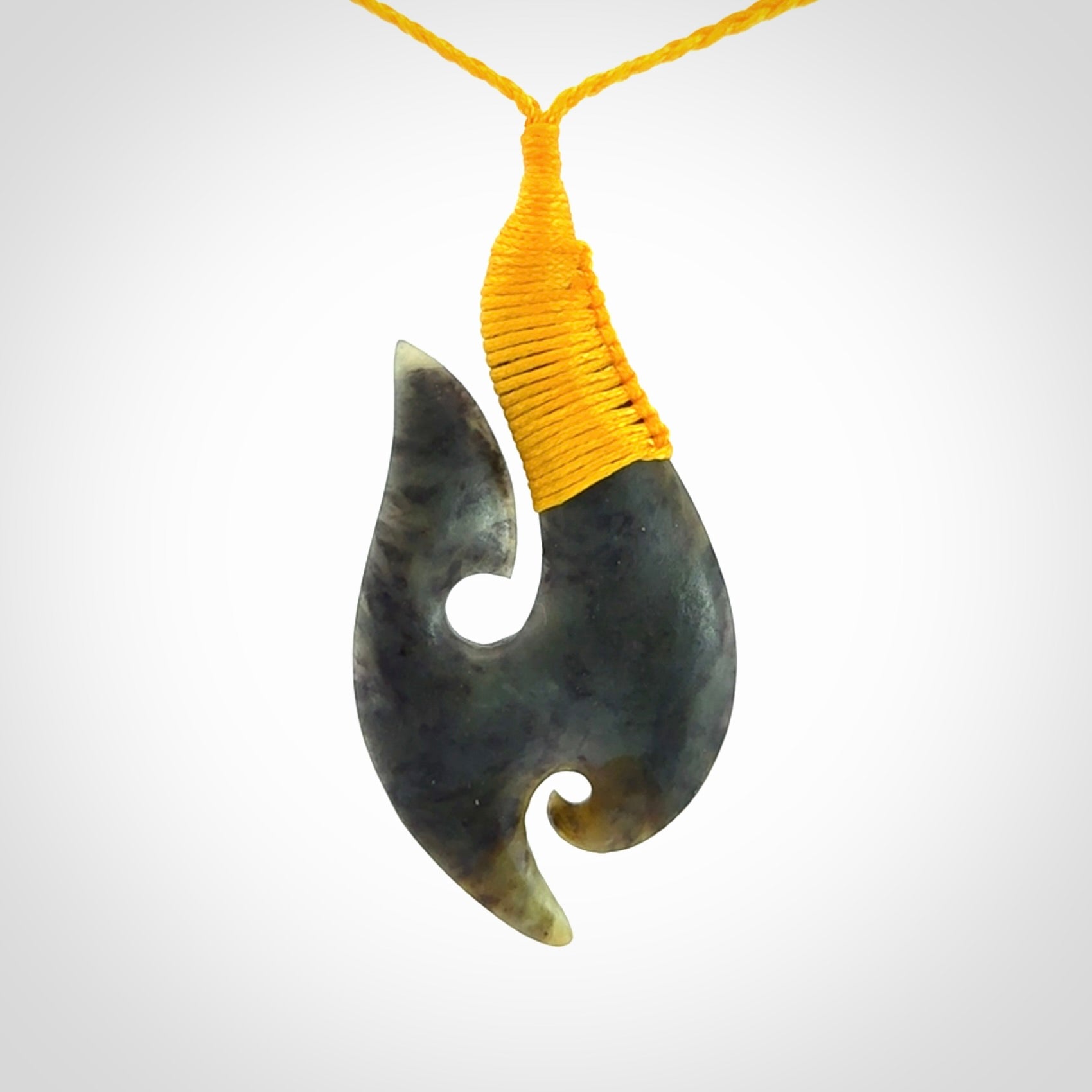 This is a beautiful jade hook with a little decorative koru carved into the bottom. It is a chunky piece but beautifully balanced so doesn't look heavy. The cord and the binding on the top is a yellow colour.
