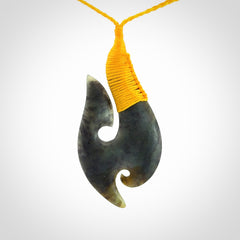 This is a beautiful jade hook with a little decorative koru carved into the bottom. It is a chunky piece but beautifully balanced so doesn't look heavy. The cord and the binding on the top is a yellow colour.