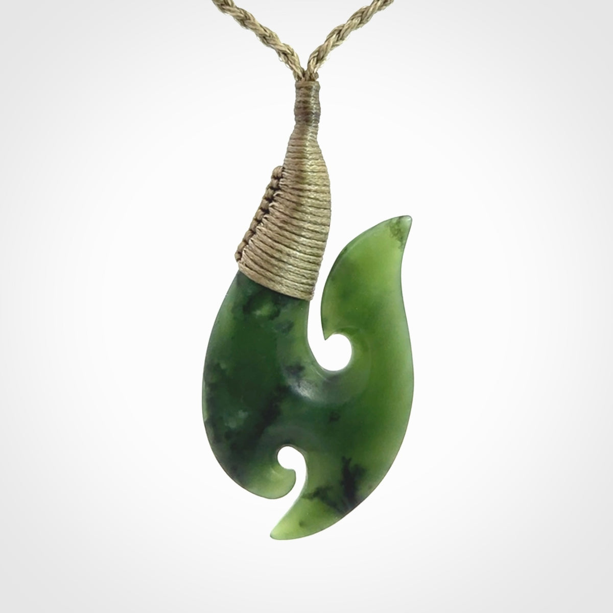 This is a beautiful jade hook with a little decorative koru carved into the bottom. It is a chunky piece but beautifully balanced so doesn't look heavy. The cord and the binding on the top is a khaki colour.