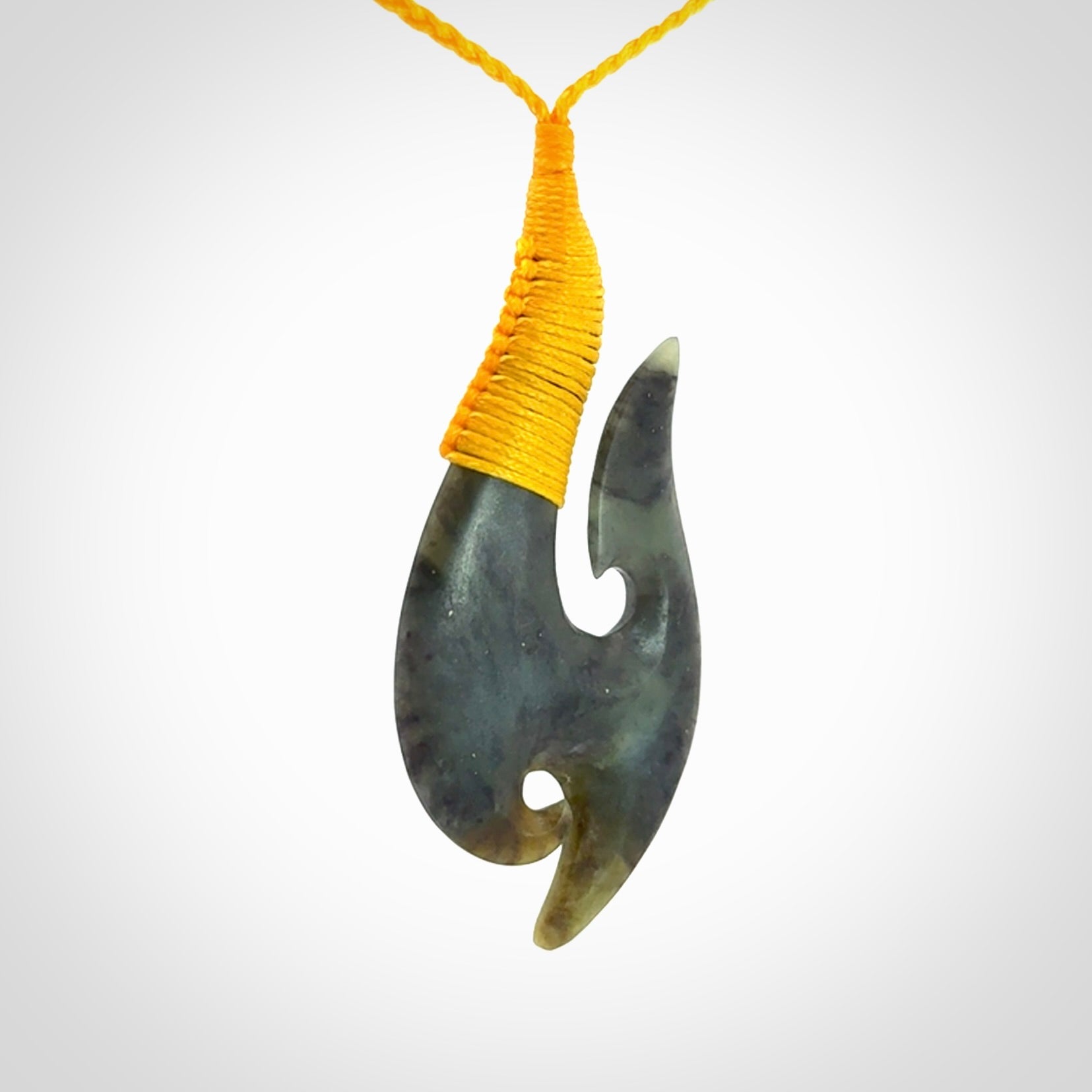 This is a beautiful jade hook with a little decorative koru carved into the bottom. It is a chunky piece but beautifully balanced so doesn't look heavy. The cord and the binding on the top is a yellow colour.