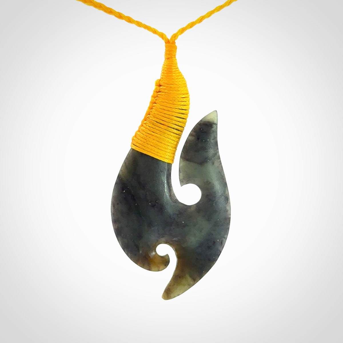 This is a beautiful jade hook with a little decorative koru carved into the bottom. It is a chunky piece but beautifully balanced so doesn't look heavy. The cord and the binding on the top is a yellow colour.