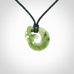 New Zealand Koru Manaia. Hand carved small jade koropepe pendant. Made in New Zealand. Real Jade, pounamu. Provided with an adjustable Manuka Green cord and packaged in a woven kete pouch.