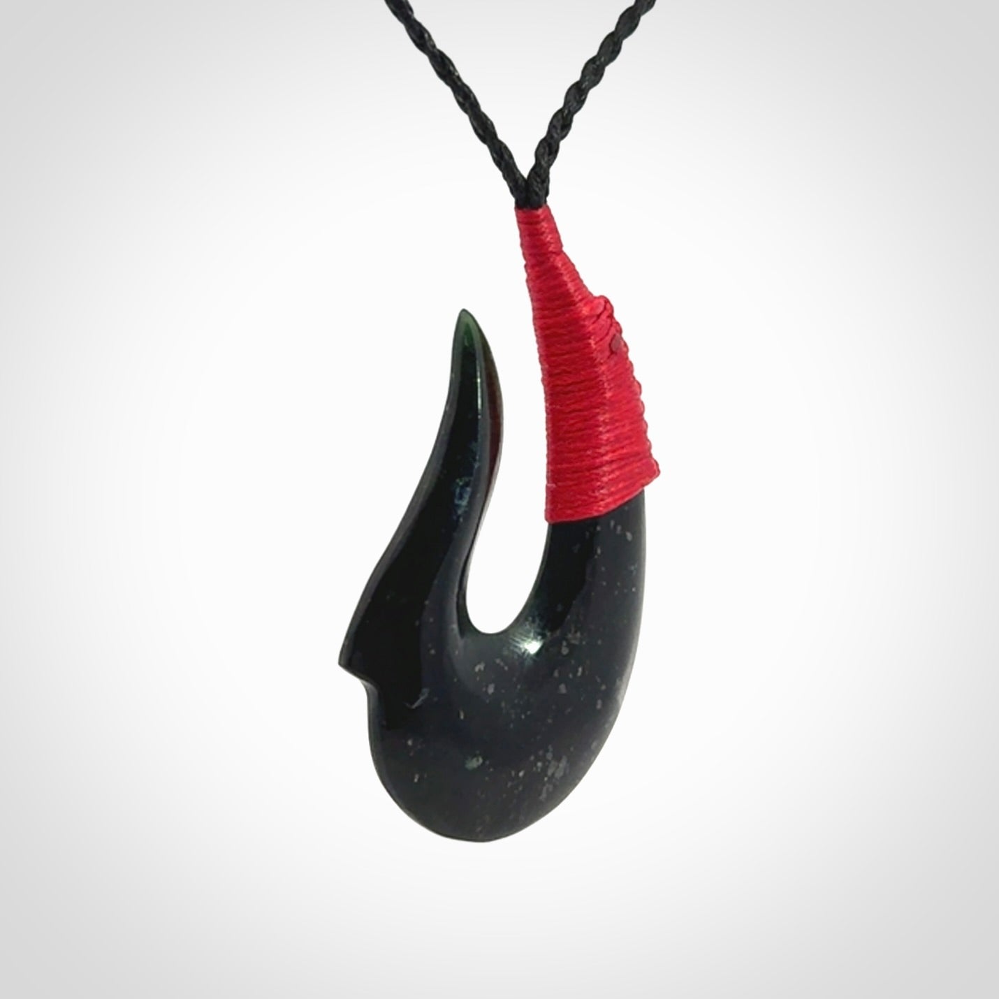 This photo shows a New Zealand Tangiwai hook, or matau, pendant. The plaited cord is black and the length can be adjusted.