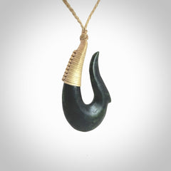 This photo shows a greenstone hook, or matau, pendant. It is a beautiful deep green jade. The cord is plaited oat coloured and the length can be adjusted.