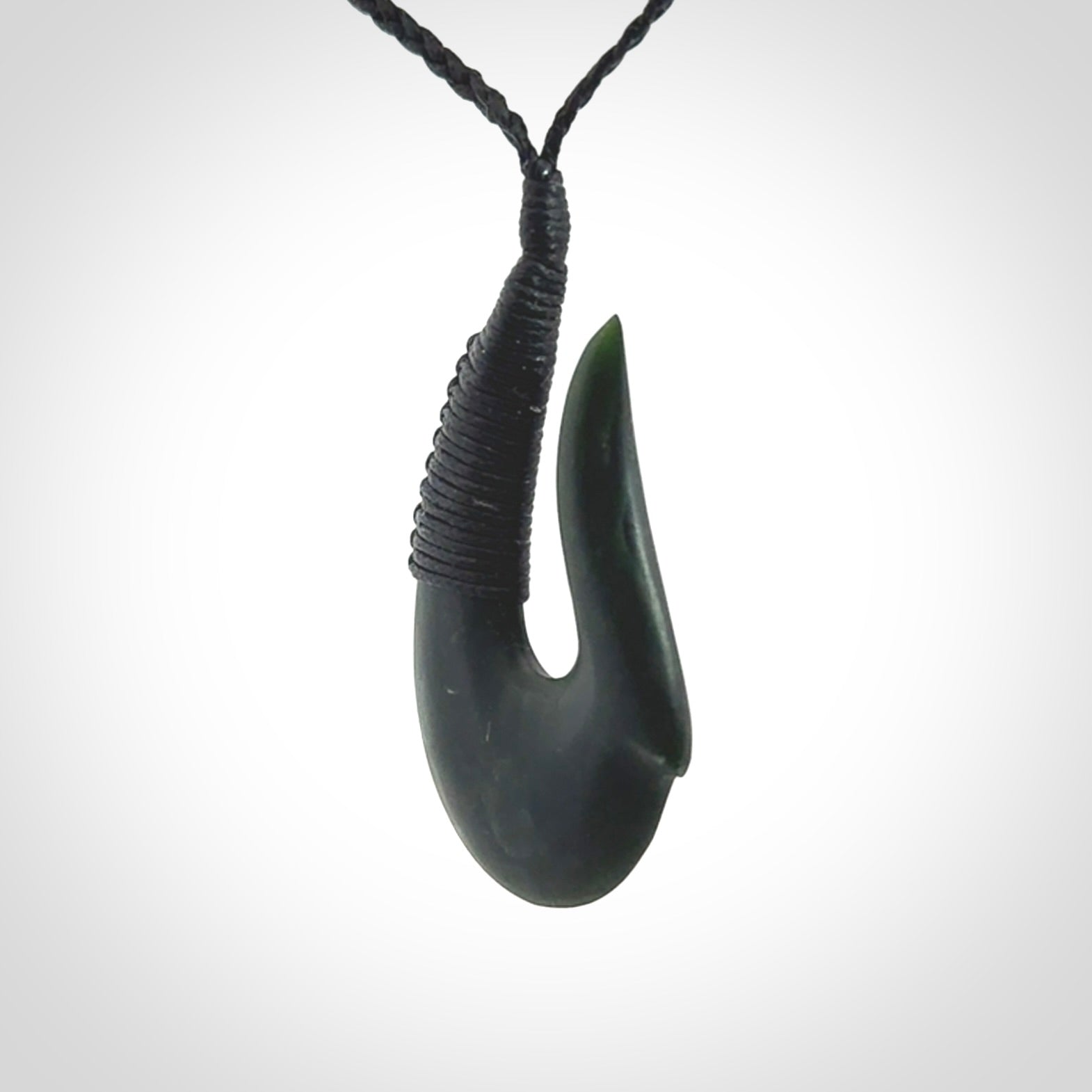 This photo shows a greenstone hook, or matau, pendant. It is a beautiful deep green jade. The cord is plaited and the length can be adjusted.