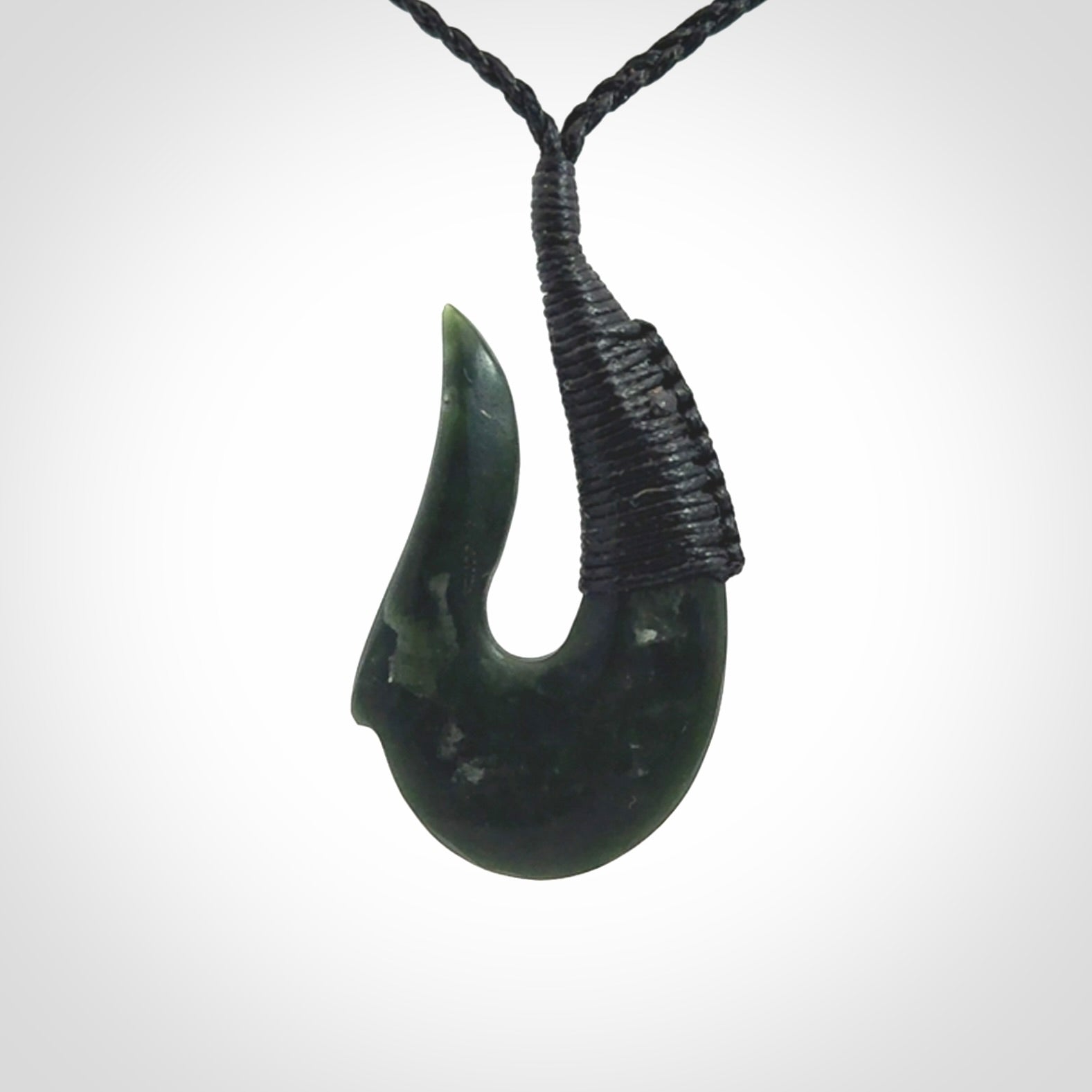 This photo shows a greenstone hook, or matau, pendant. It is a beautiful deep green jade. The cord is plaited and the length can be adjusted.