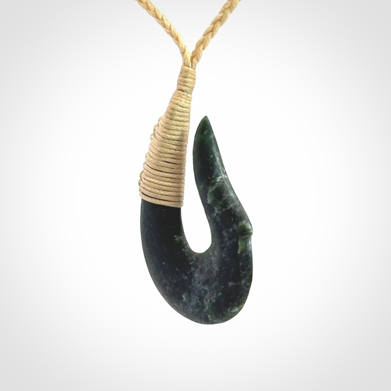 This photo shows a greenstone hook, or matau, pendant. It is a beautiful deep green jade. The cord is plaited and the length can be adjusted.