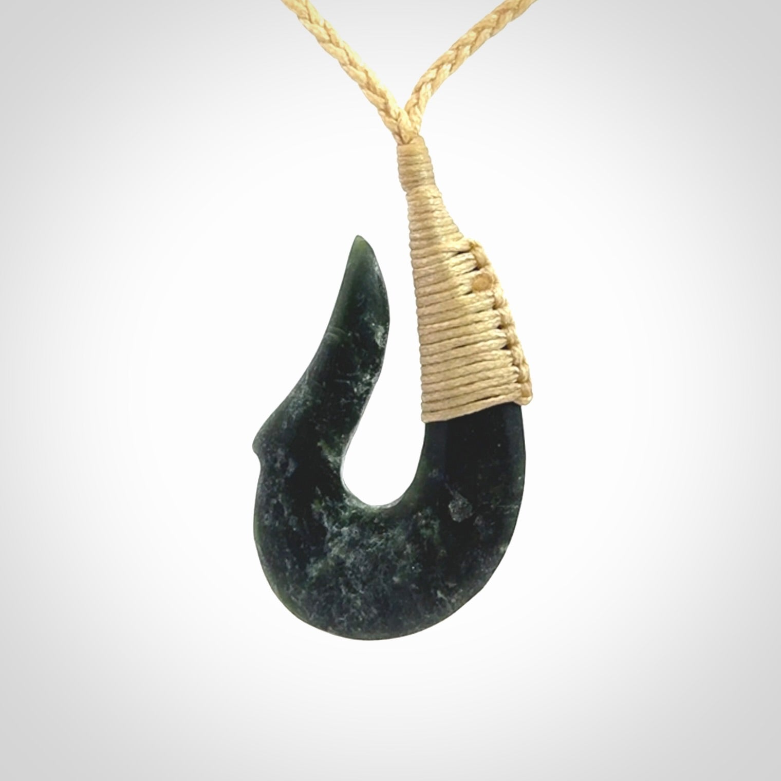 This photo shows a greenstone hook, or matau, pendant. It is a beautiful deep green jade. The cord is plaited and the length can be adjusted.