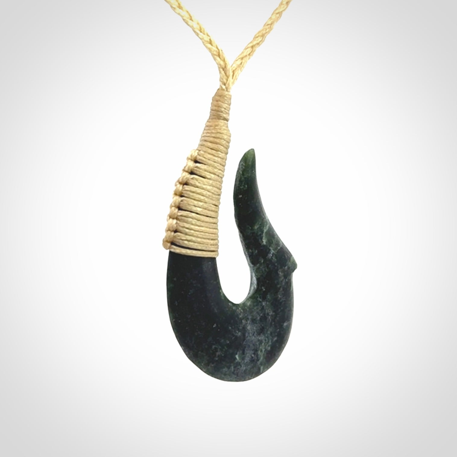 This photo shows a greenstone hook, or matau, pendant. It is a beautiful deep green jade. The cord is plaited and the length can be adjusted.