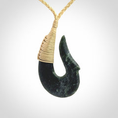 This photo shows a greenstone hook, or matau, pendant. It is a beautiful deep green jade. The cord is plaited and the length can be adjusted.