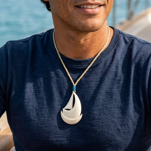 man wearing bone sailboat pendant