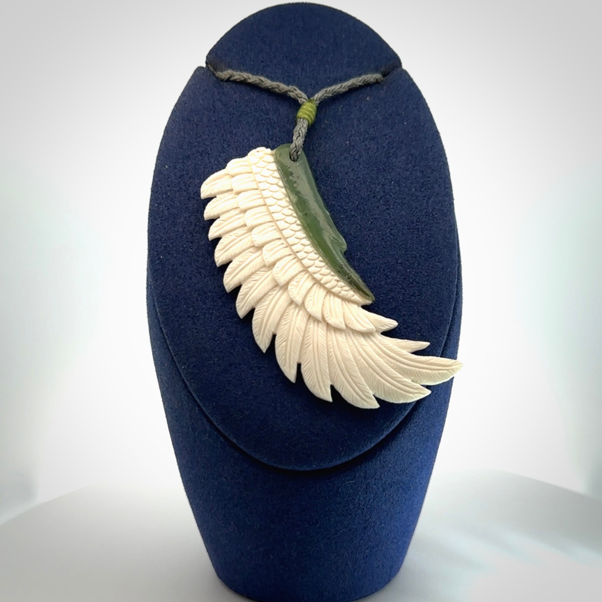 This photo shows a beautiful bone and jade wing pendant.