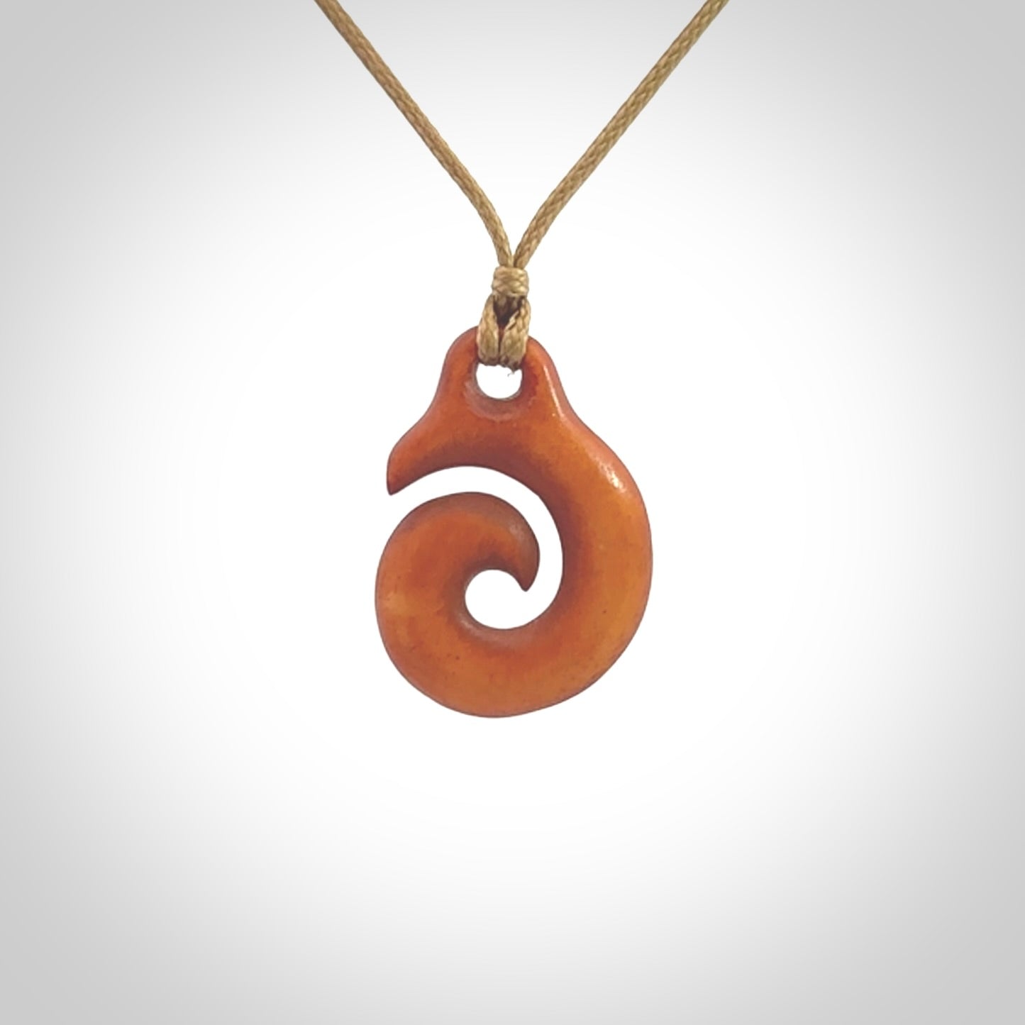 Stained natural cow bone hook with koru pendant. Hand carved by Yuri Terenyi in New Zealand. Koru design pendant for sale online. Stained bone koru necklace with adjustable cord. Free delivery worldwide.