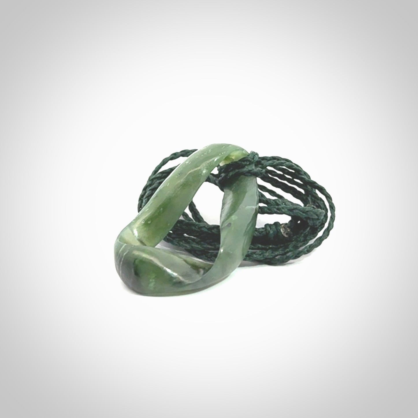 This little piece is a hand carved möbius ribbon pendant. We've carved this from Nephrite Jade. It has very subtle colour variations in the stone and is a delightful, small and artistic piece of jewellery.