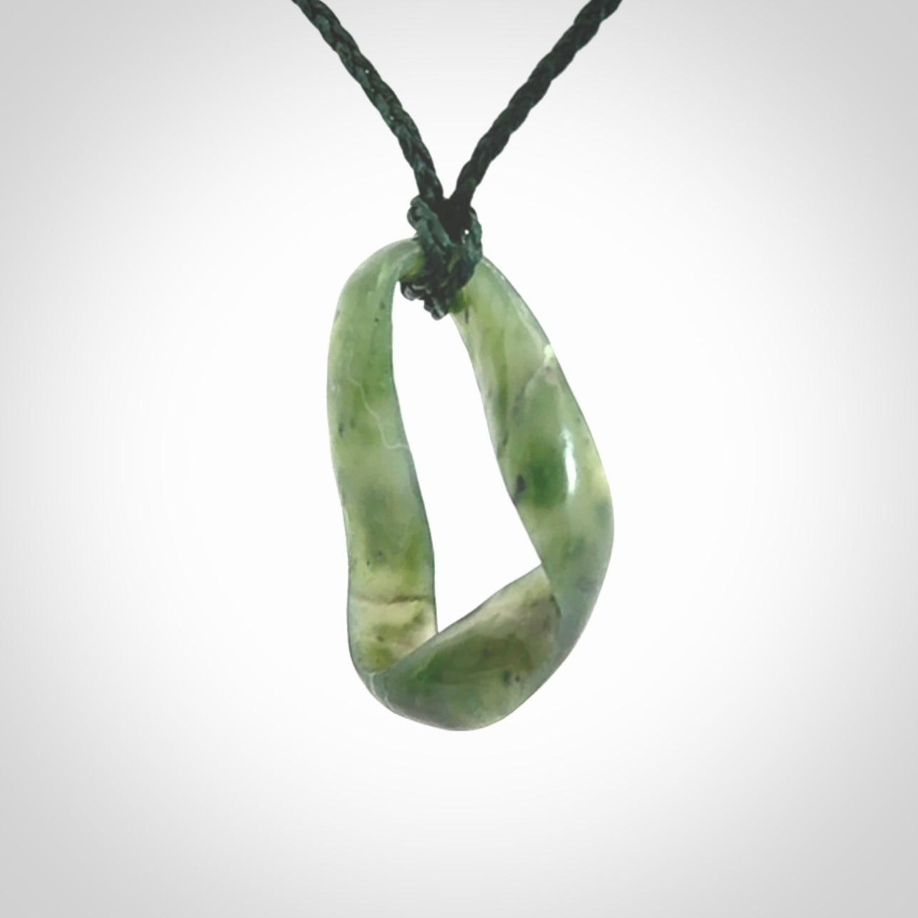 This little piece is a hand carved möbius ribbon pendant. We've carved this from Nephrite Jade. It has very subtle colour variations in the stone and is a delightful, small and artistic piece of jewellery.