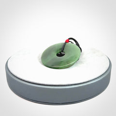 This picture shows a large hand-carved disc pendant. It is carved from British Columbian jade and is suspended from a hand-plaited, black cord. Free delivery worldwide. BC Jade contemporary necklace.